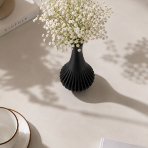3D printed spiral vase in black PLA styled with baby's breath on a console table